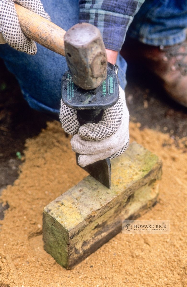 using a club hammer and bolster to cut a brick in half